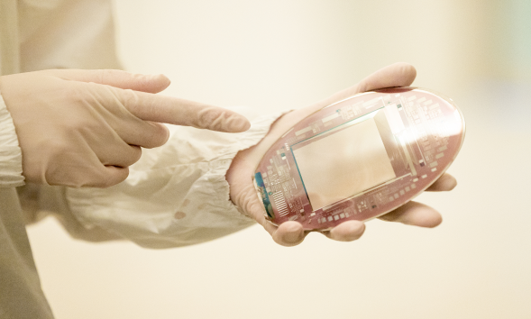 Gloved person pointing to a microelectronics device